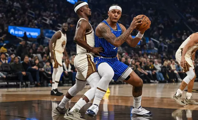 Orlando Magic forward Paolo Banchero (5) ,right, dribbles against Golden State Warriors forward Jimmy Butler III (10) ,left, during the first half of an NBA basketball game, Monday, Dec. 22, 2025, in San Francisco (AP Photo/Justine Willard)
