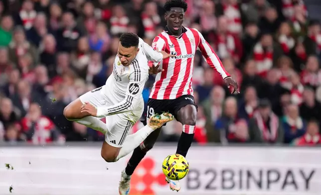Real Madrid's Kylian Mbappe, left, challenges for the ball with Athletic Bilbao's Adama Boiro during the Spanish La Liga soccer match between Athletic Bilbao and Real Madrid in Bilbao, Spain, Wednesday, Dec. 3, 2025. (AP Photo/Jose Breton)