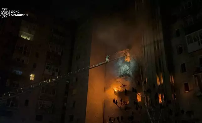 In this photo provided by the Ukrainian Emergency Services on Monday, Dec. 8, 2025, a rescue worker puts out a fire of a residential building damaged by a Russian strike in Sumy region, Ukraine. (Ukrainian Emergency Service via AP)