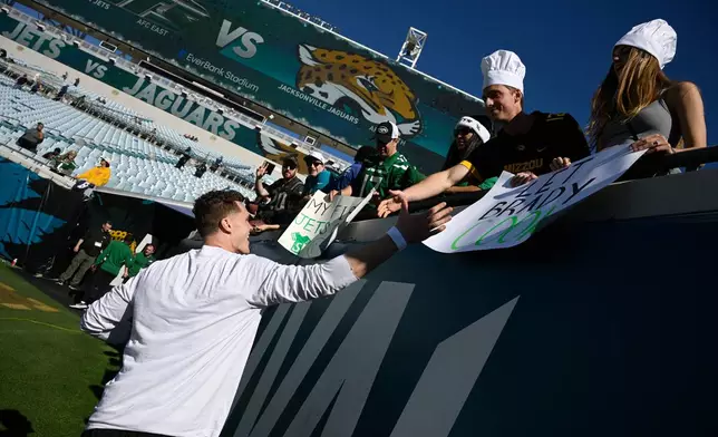 New York Jets quarterback Brady Cook (4) greets fans before an NFL football game against the Jacksonville Jaguars, Sunday, Dec. 14, 2025, in Jacksonville, Fla. (AP Photo/Phelan M. Ebenhack)