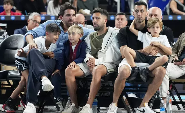 Former Inter Miami soccer players Jordi Alba, center, and Sergio Busquets, right, sit alongside the court at the Miami Tennis Invitational tournament, Monday, Dec. 8, 2025, in Miami. (AP Photo/Lynne Sladky)