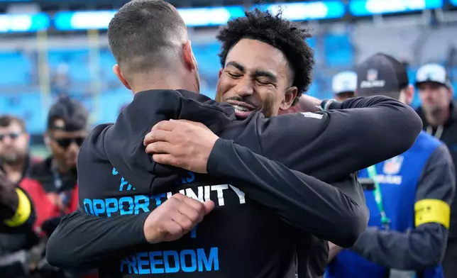 Carolina Panthers head coach Dave Canales greets quarterback Bryce Young after their win against the Tampa Bay Buccaneers in an NFL football game, Sunday, Dec. 21, 2025, in Charlotte, N.C. (AP Photo/Jacob Kupferman)