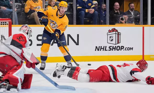 Nashville Predators left wing Erik Haula (56) shoots the puck over Carolina Hurricanes defenseman Jaccob Slavin (74) during the second period of an NHL hockey game Wednesday, Dec. 17, 2025, in Nashville, Tenn. (AP Photo/George Walker IV)