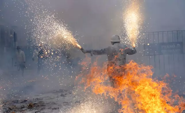 Revellers take part in the Els Enfarinats festival, a battle using flour, eggs and firecrackers, in the town of Ibi near Alicante, Spain, Sunday Dec. 28, 2025. (AP Photo/Alberto Saiz)