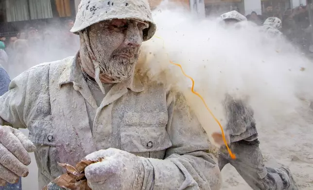 Revellers take part in the Els Enfarinats festival, a battle using flour, eggs and firecrackers, in the town of Ibi near Alicante, Spain, Sunday Dec. 28, 2025. (AP Photo/Alberto Saiz)