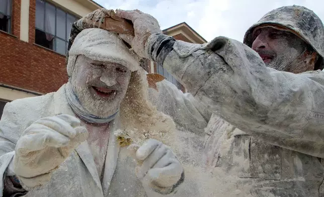 Revellers take part in the Els Enfarinats festival, a battle using flour, eggs and firecrackers, in the town of Ibi near Alicante, Spain, Sunday Dec. 28, 2025. (AP Photo/Alberto Saiz)