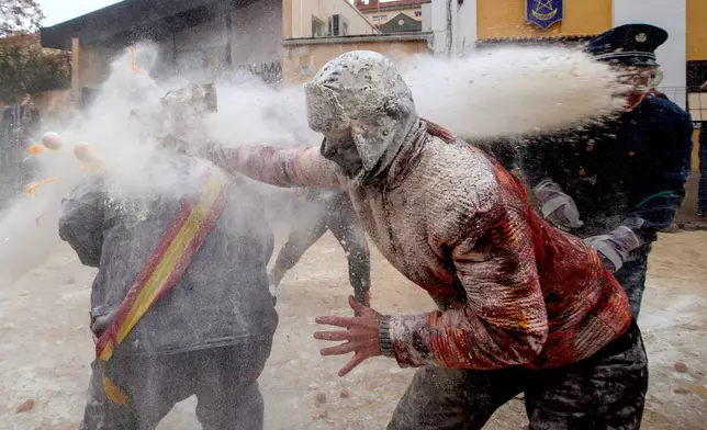 Revellers take part in the Els Enfarinats festival, a battle using flour, eggs and firecrackers, in the town of Ibi near Alicante, Spain, Sunday Dec. 28, 2025. (AP Photo/Alberto Saiz)