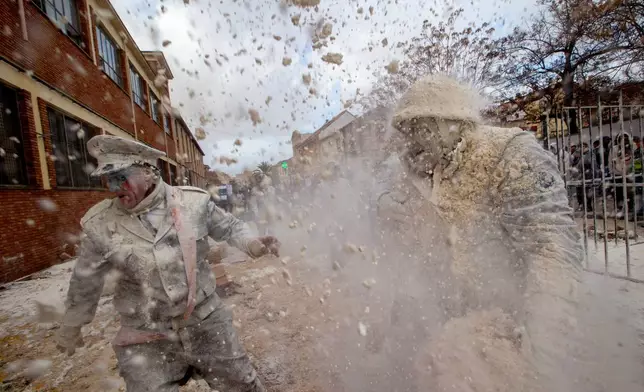 Revellers take part in the Els Enfarinats festival, a battle using flour, eggs and firecrackers, in the town of Ibi near Alicante, Spain, Sunday Dec. 28, 2025. (AP Photo/Alberto Saiz)