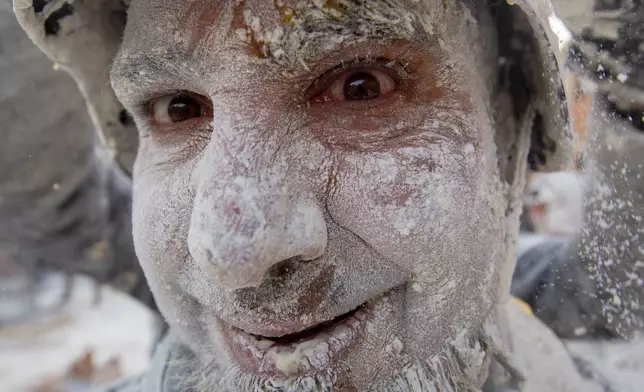 A reveller takes part in the Els Enfarinats festival, a battle using flour, eggs and firecrackers, in the town of Ibi near Alicante, Spain, Sunday Dec. 28, 2025. (AP Photo/Alberto Saiz)