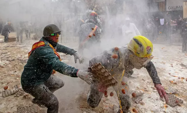 Revellers take part in the Els Enfarinats festival, a battle using flour, eggs and firecrackers, in the town of Ibi near Alicante, Spain, Sunday Dec. 28, 2025. (AP Photo/Alberto Saiz)