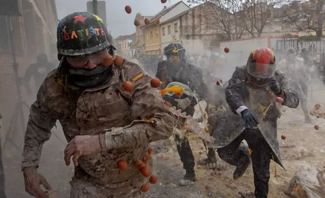 Revellers take part in the Els Enfarinats festival, a battle using flour, eggs and firecrackers, in the town of Ibi near Alicante, Spain, Sunday Dec. 28, 2025. (AP Photo/Alberto Saiz)