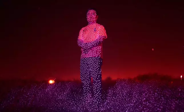 Retired Chinese official Li Chuanliang, who openly criticized the Chinese government after seeing first-hand how surveillance technology built up the government's power and is now being accused of corruption by Beijing, is illuminated by cellphone infrared facial recognition beams as he stands for a photo in the oil fields of Midland, Texas, where he's currently living in exile, Oct. 11, 2025. (AP Photo/David Goldman)