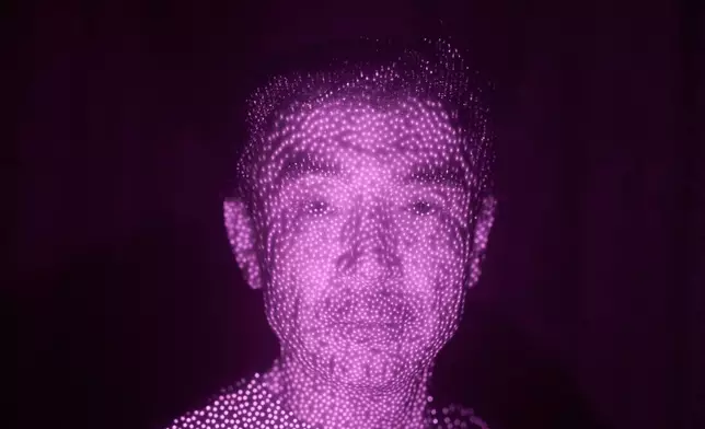 Former Xinjiang government engineer Nureli Abliz, who saw firsthand how surveillance technology flagged thousands of people in China for detention, even when they had committed no crime, is illuminated by cellphone infrared facial recognition beams as he sits for a photo in Mannheim, Germany, where he's currently living in exile, July 23, 2025. (AP Photo/David Goldman)
