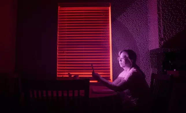 Guigiu Chen, who escaped China with her daughters after her husband, prominent rights lawyer Xie Yang, was detained, is illuminated by cellphone infrared facial recognition beams as she sits for a photo, Oct. 12, 2025, in Midland, Texas, where she's living in exile. (AP Photo/David Goldman)