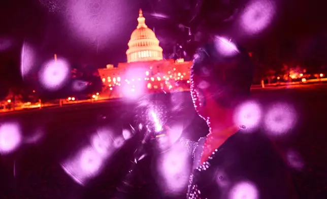 Infrared facial recognition beams are emitted from a cellphone held by a Uyghur man, who asked to remain anonymous for safety reasons, as he’s photographed in front of the U.S. Capitol, Oct. 16, 2025, in Washington, where he’s living in exile after escaping China. (AP Photo/David Goldman)