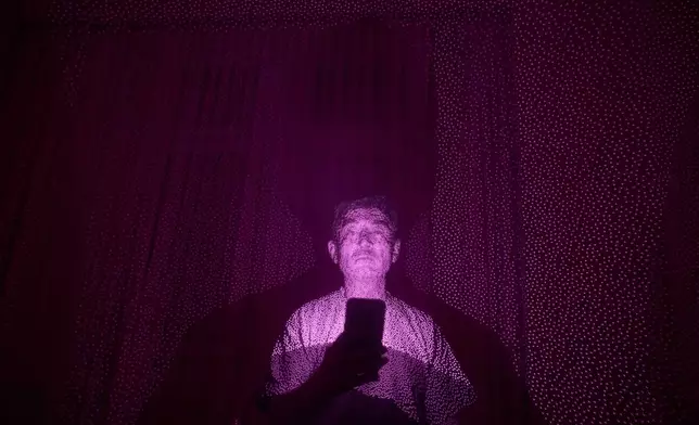 Former Xinjiang government engineer Nureli Abliz, who saw firsthand how surveillance technology flagged thousands of people in China for detention, even when they had committed no crime, is illuminated by cellphone infrared facial recognition beams as he sits for a photo in Mannheim, Germany, where he is currently living in exile, July 23, 2025. (AP Photo/David Goldman)