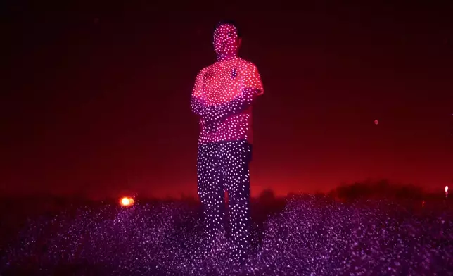 Retired Chinese official Li Chuanliang, who openly criticized the Chinese government after seeing first-hand how surveillance technology built up the government's power and is now being accused of corruption by Beijing, is illuminated by cellphone infrared facial recognition beams as he stands for a photo in the oil fields of Midland, Texas, where he's currently living in exile, Oct. 11, 2025. (AP Photo/David Goldman)