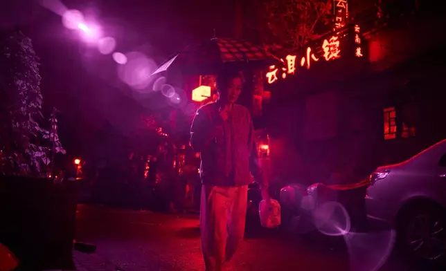 An infrared beam of light shines from a security camera watching over the Beigulou alleyway in Beijing as a pedestrian passes, Oct. 9, 2025. (AP Photo/Ng Han Guan)