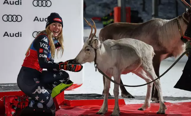 FILE - United States' Mikaela Shiffrin feeds a deer on the podium after winning an alpine ski, women's World Cup slalom, in Levi, Finland, on Nov. 15, 2025. (AP Photo/Marco Trovati, File)