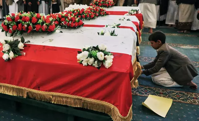 A boy prays in front of his relative coffin during the funeral of 5 Houthi leaders, who they said were killed during previous Israeli airstrikes, at the people's mosque in Sanaa, Yemen, Thursday, Dec. 25, 2025. (AP Photo/Osamah Abdulrahman)