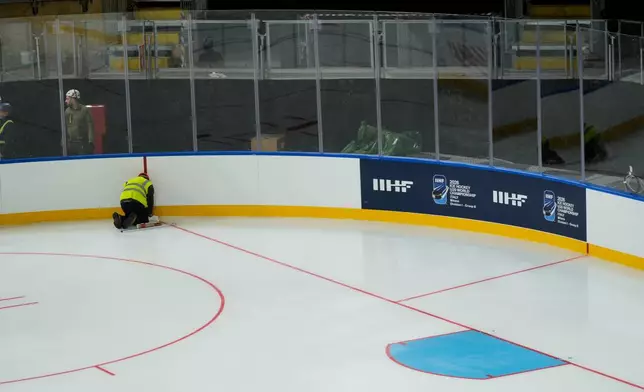A worker prepares the Ice Skating Arena where some Ice Hockey matches of the Milan Cortina 2026 Winter Olympics will take place, in Rho, outskirt of Milan, Friday, Dec.5, 2025. (AP Photo/Luca Bruno)