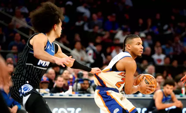Orlando Magic guard Anthony Black, left, grabs the jersey of New York Knicks guard Miles McBride during the first half of an NBA basketball game Sunday, Dec. 7, 2025, in New York. (AP Photo/John Munson)