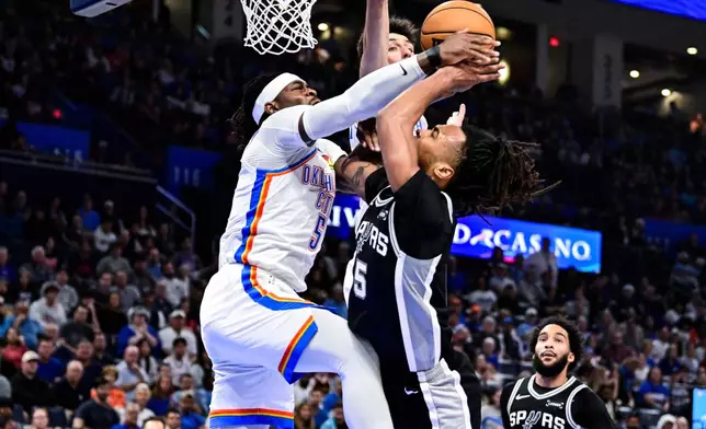 Oklahoma City Thunder guard Luguentz Dort (5) block against San Antonio Spurs guard Stephon Castle (5) during the first half of an NBA basketball game, Thursday, Dec. 25, 2025, in Oklahoma City. (AP Photo/Gerald Leong)