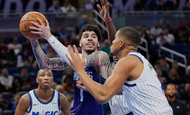 Charlotte Hornets guard Lamelo Ball (1) looks to pass the ball as Orlando Magic center Orlando Robinson, right, defends during the second half of an NBA basketball game, Friday, Dec. 26, 2025, in Orlando, Fla. (AP Photo/John Raoux)