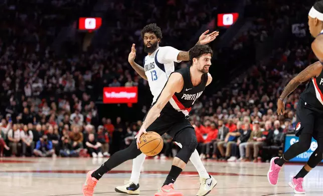 Portland Trail Blazers forward Deni Avdija, middle, drives to the basket against Dallas Mavericks forward Naji Marshall, left, during the second half of an NBA basketball game Monday Dec. 29, 2025, in Portland, Ore. (AP Photo/Howard Lao)