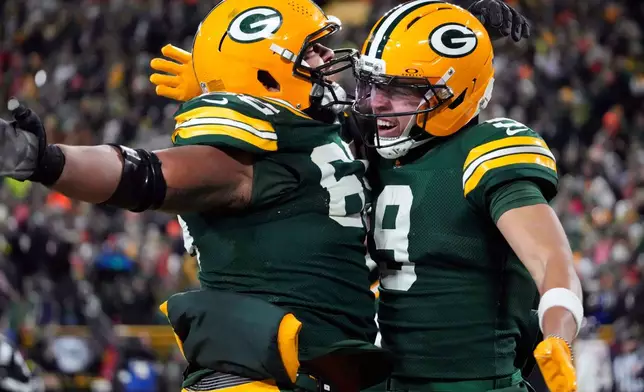 Green Bay Packers wide receiver Christian Watson (9) celebrates with guard Aaron Banks (65) after scoring a touchdown against the Chicago Bears during the second half of an NFL football game Sunday, Dec. 7, 2025, in Green Bay, Wis. (AP Photo/Morry Gash)