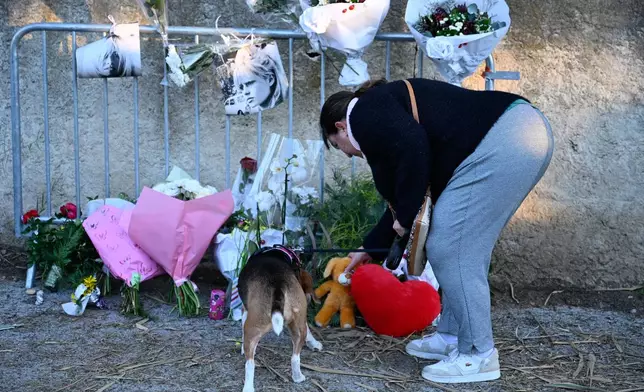 A woman and her dog lay a Teddy bear at actor Brigitte Bardot's home in Saint-Tropez, southern France, Sunday, Dec. 28, 2025 after the French 1960s sex symbol who became one of the greatest screen sirens of the 20th century and later a militant animal rights activist and far-right supporter, has died. She was 91. (AP Photo/Philippe Magoni)