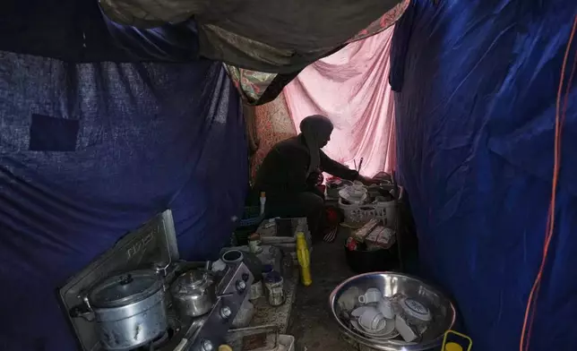 Saadia Abu Duheir, a mother of six, organizes her kitchen inside a temporary tent set up over the rubble of her family's collapsed home in the Sheikh Radwan neighborhood of Gaza City, Wednesday, Nov. 26, 2025. (AP Photo/Jehad Alshrafi)