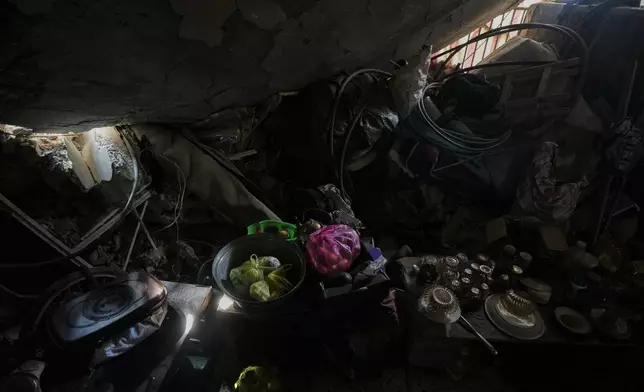 Food and pottery sit amid the rubble in the kitchen of the Abu Shaqfa family, a small sign of daily life beneath the roof of their partially collapsed home in Jabaliya, Gaza City, Friday, Nov. 21, 2025. (AP Photo/Jehad Alshrafi)