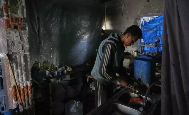 Omar Qutay washes dishes in the kitchen of his partially destroyed home in the Al-Karama neighborhood of Gaza City, Wednesday, Nov. 24, 2025. (AP Photo/Jehad Alshrafi)