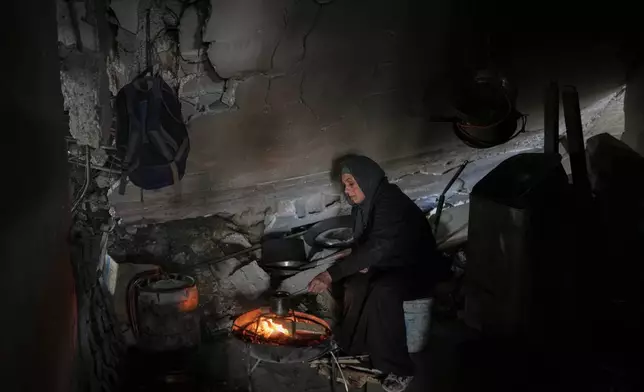 Amani Halawa warms a beverage over a fire in a dilapidated room, making do amid the rubble of her damaged home in Jabaliya, Gaza City, Tuesday, Nov. 25, 2025.(AP Photo/Jehad Alshrafi)