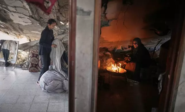 Amani Halawa lights a fire as her daughter Aya arranges laundry in their damaged home in Jabaliya, Gaza City, Tuesday, Nov. 25, 2025.(AP Photo/Jehad Alshrafi)