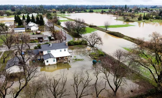 Floodwaters cover a yard and fields following heavy rains, on Monday, Dec. 22, 2025, in Redding, Calif. (AP Photo/Noah Berger)