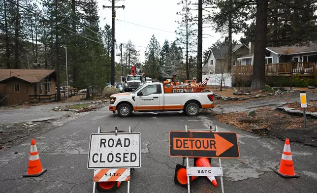 Workers work to restore power after severe storms, Thursday, Dec. 25, 2025, in Wrightwood, Calif. (AP Photo/William Liang)