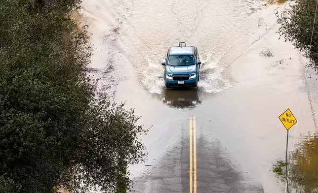 A car drives down a flooded road following heavy rains, on Monday, Dec. 22, 2025, in Redding, Calif. (AP Photo/Noah Berger)