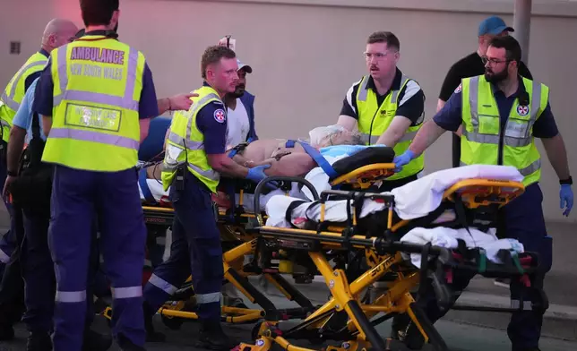 Emergency workers transport a person on a stretcher after a reported shooting at Bondi Beach in Sydney, Sunday, Dec. 14, 2025. (AP Photo/Mark Baker)