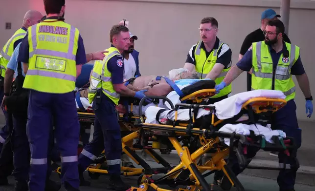 Emergency workers transport a person on a stretcher after a reported shooting at Bondi Beach in Sydney, Sunday, Dec. 14, 2025. (AP Photo/Mark Baker)
