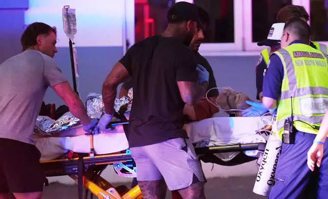 Emergency workers transport a person on a stretcher after a reported shooting at Bondi Beach in Sydney, Sunday, Dec. 14, 2025. (AP Photo/Mark Baker)