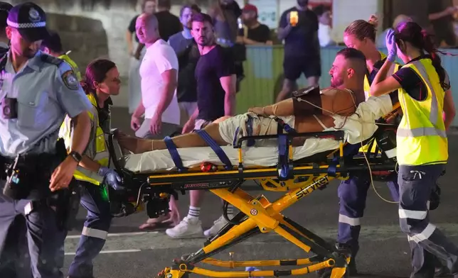 Emergency workers transport a person on a stretcher after a reported shooting at Bondi Beach in Sydney, Sunday, Dec. 14, 2025. (AP Photo/Mark Baker)