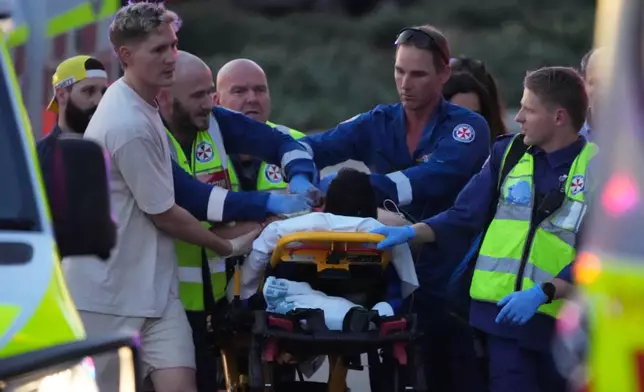 Emergency workers transport a person on a stretcher after a reported shooting at Bondi Beach, in Sydney, Sunday, Dec. 14, 2025. (AP Photo/Mark Baker)