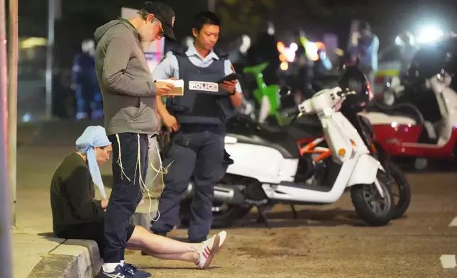 Bystanders stay where police cordon off an area at Bondi Beach after a reported shooting in Sydney, Sunday, Dec. 14, 2025. (AP Photo/Mark Baker)
