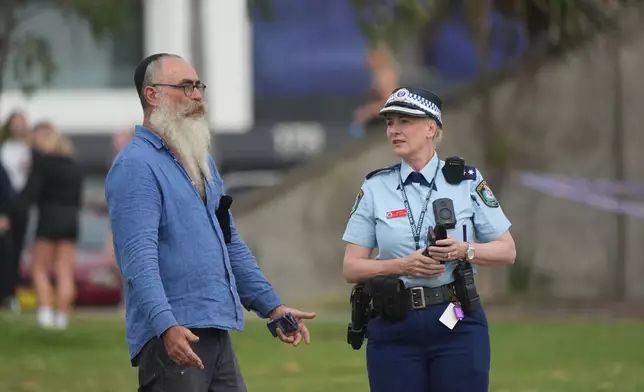 A police officer talks to a member of the public following a shooting the day prior at Sydney's Bondi Beach, Monday, Dec. 15, 2025. (AP Photo/Mark Baker)