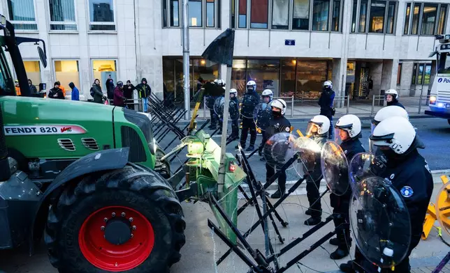 Police guard a barrier as farmers drive their tractors to block a main boulevard during a demonstration outside a gathering of European leaders at the EU Summit in Brussels, Thursday, Dec. 18, 2025. (AP Photo/Marius Burgelman)