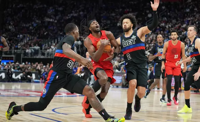 Portland Trail Blazers forward Jerami Grant, center, drives against Detroit Pistons guards Javonte Green, left, and Cade Cunningham during the first half of an NBA basketball game Friday, Dec. 5, 2025, in Detroit. (AP Photo/Ryan Sun)