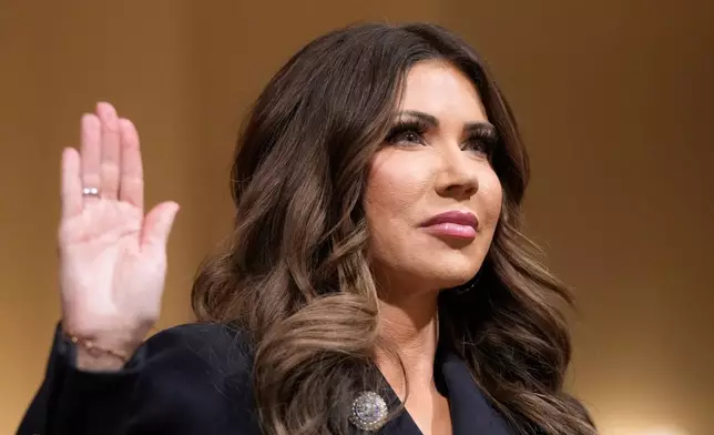 Homeland Security Secretary Kristi Noem raise her arm before the House Committee on Homeland Security on Capitol Hill in Washington, Thursday, Dec. 11, 2025. (AP Photo/Mark Schiefelbein)