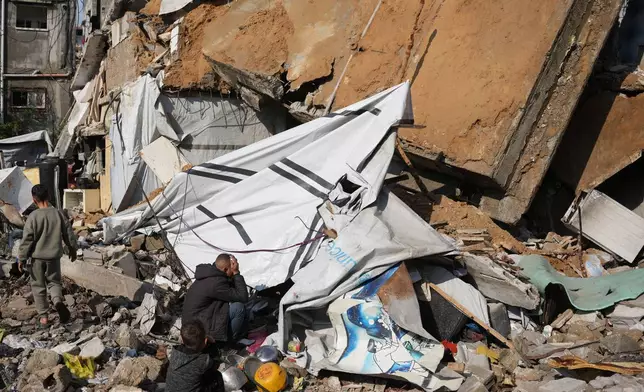 Alaa al-Hosari sits on the rubble of his house that collapsed, killing, according to Al-Shafa Hospital officials, at least one person and leaving several others injured in Gaza City, Tuesday, Dec. 16, 2025. (AP Photo/Abdel Kareem Hana)